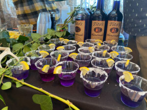 a table topped with glasses filled with purple liquid and lemon wedges