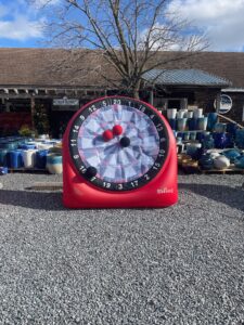 a red clock sitting on top of a gravel field