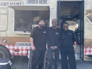 three people standing in front of a food truck