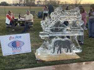 people are standing around an ice sculpture in the grass