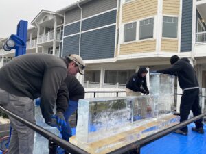 three men working on an ice sculpture in front of a building