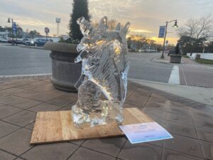 a glass horse statue on a wooden stand