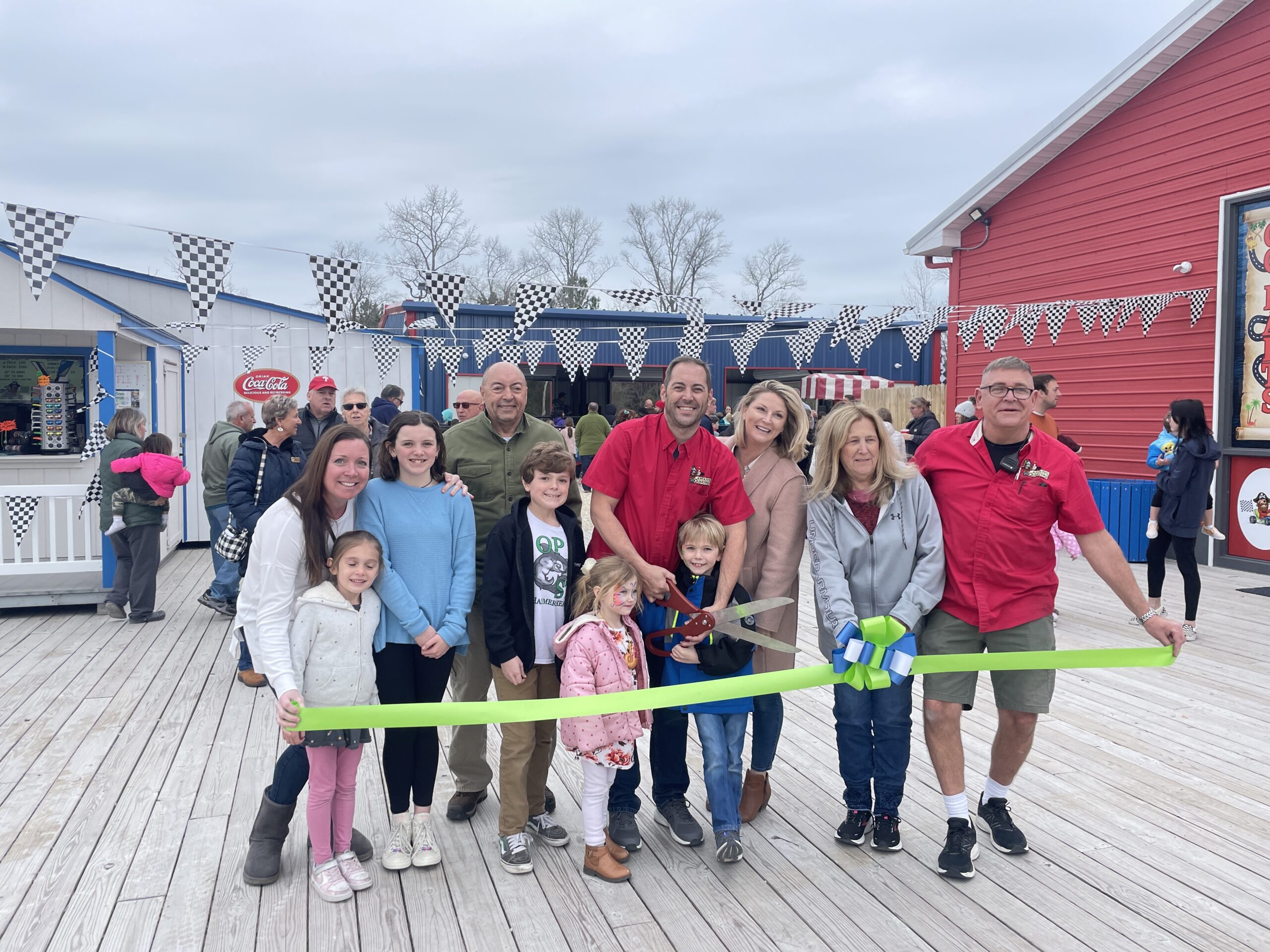 a group of people standing on a boardwalk holding a ribbon