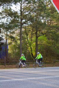 two bicyclists are riding down the street in front of a stop sign