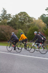 three people riding bikes down the street