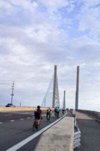 a group of bicyclists riding across a bridge