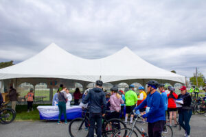 a group of bicyclists standing around a tent