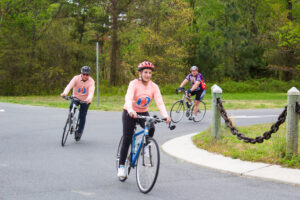 three people riding bikes on a paved road