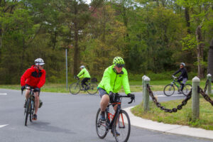 two people riding bikes on a paved road