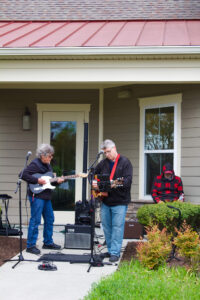 two people playing music outside of a house