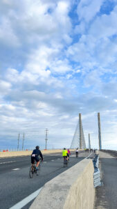 people riding bikes on a bridge over water