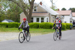 two bicyclists are riding down the street in front of a house