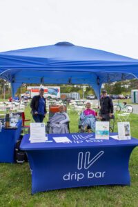 a group of people sitting under a blue tent