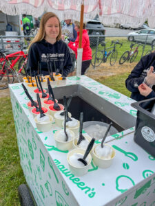 a woman standing next to a table filled with cups