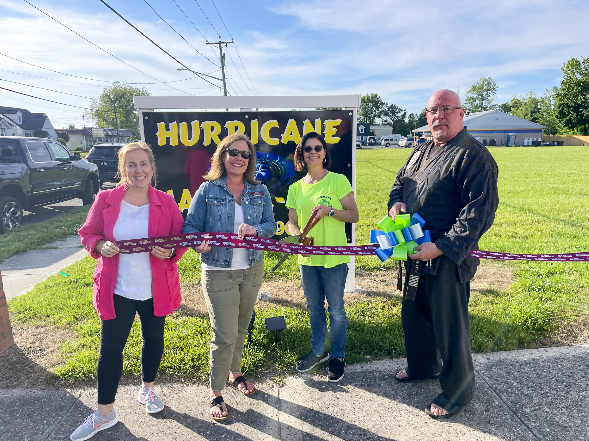 a group of people holding a ribbon in front of a sign