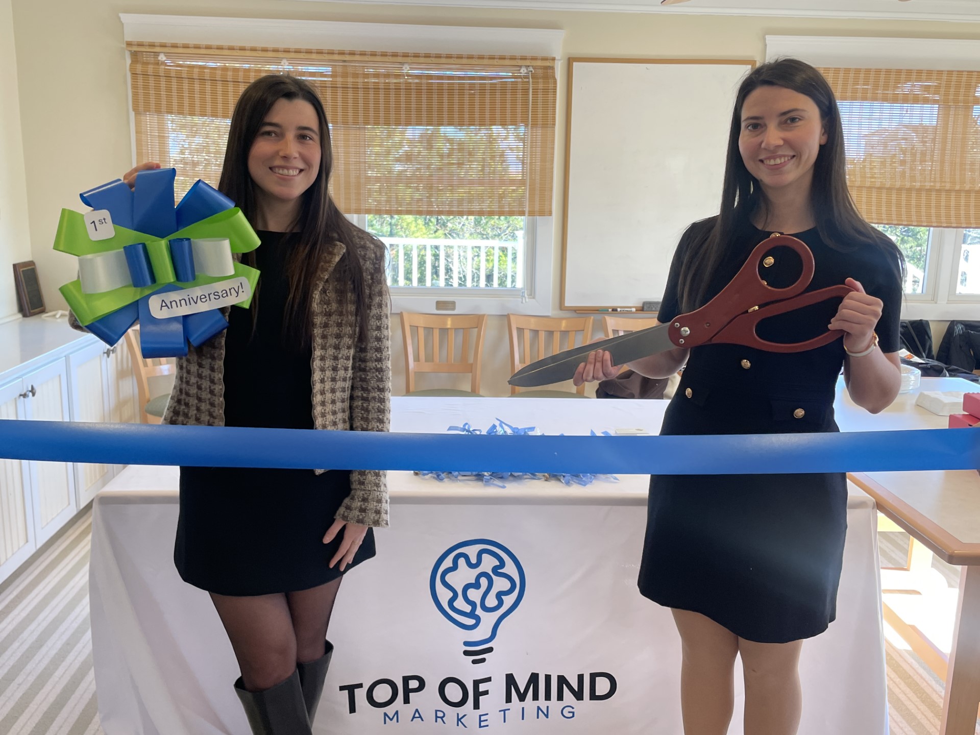 two women holding a giant pair of scissors